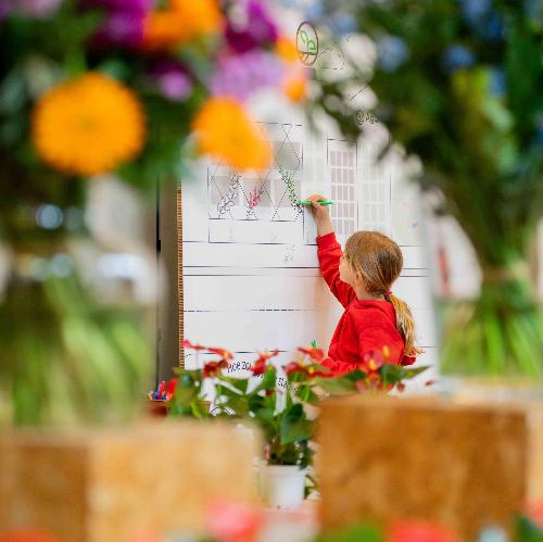 Jong tuin labo Floraliën beeld van jong meisje dat op bord tekent omringd door bloemen buiten focus